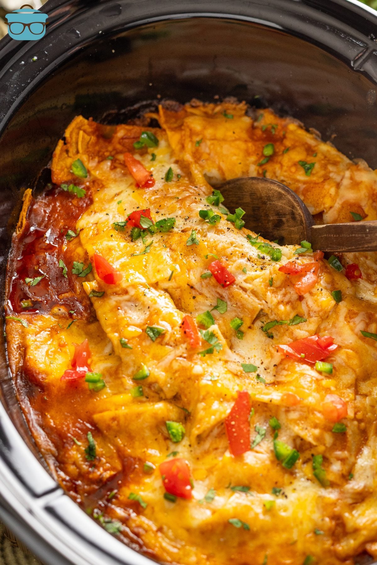 A serving spoon in a Crock Pot of Enchilada Casserole.